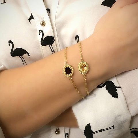 Woman wearing a pair of gold vermeil bracelets featuring garnet and citrine