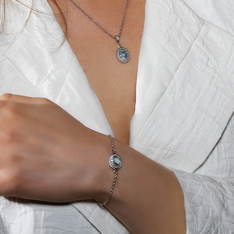 Woman wearing a sterling silver chained bracelet fashioning blue topaz.