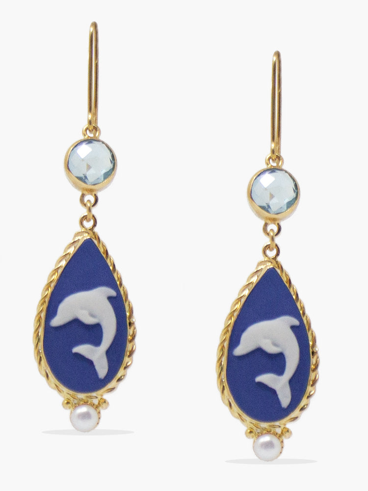 Dolphins cameo earrings by Vintouch are handcrafted from porcelain, showcasing swimming dolphins, symbolizing wisdom and salvation as per the Greek mythology, enriched with sparkling blue topaz. 