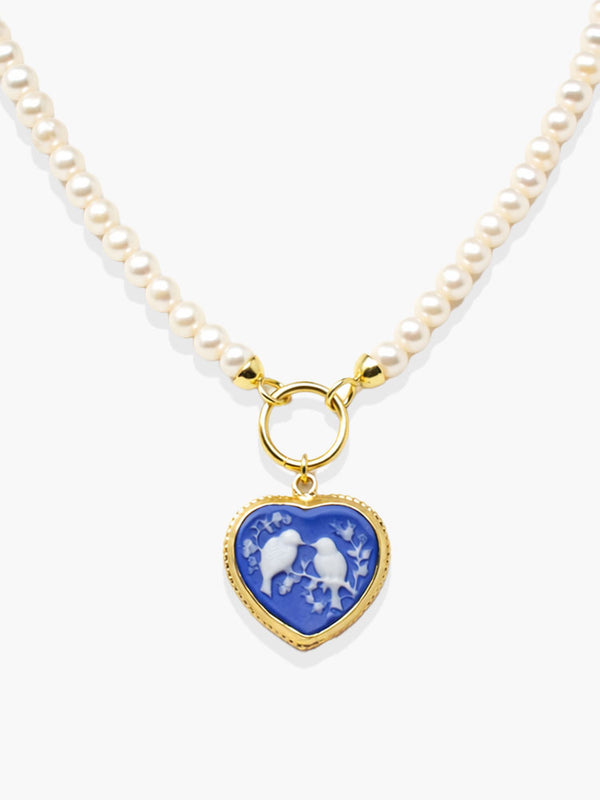 Handcrafted pearl necklace with blue heart-shaped porcelain cameo pendant depicting two birds on flowering branches, mounted in 18k gold-plated sterling silver