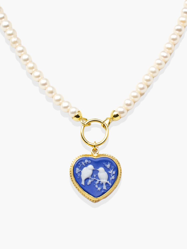 Handcrafted pearl necklace with blue heart-shaped porcelain cameo pendant depicting two birds on flowering branches, mounted in 18k gold-plated sterling silver